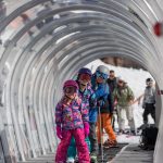 Two girls with Ski Instructor in covered carpet lift
